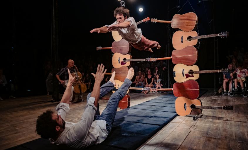 Man jumping through stack of guitars